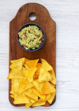 Kase guacamole Nacho Beyaz ahşap zemin üzerinde rustik ahşap tahta üzerinde ile. Yukarıdan. Üstten Görünüm. Yakın çekim.