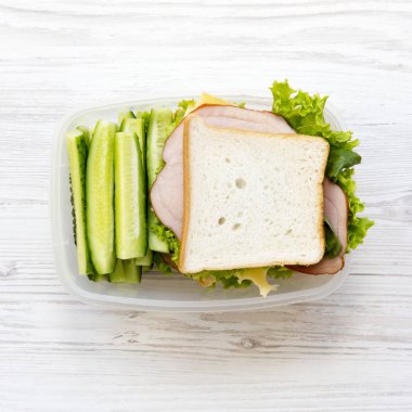 Sandviç ve sebze Beyaz ahşap yüzey, en iyi görünümü üzerinde öğle yemeği kutusu. Düz yatıyordu. Yukarıdan. 