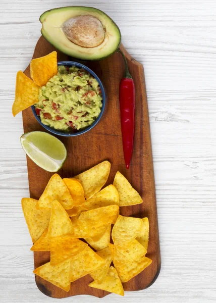Beyaz ahşap zemin üzerinde rustik ahşap tahta üzerinde guacamole ve Mısır Nacho. Üstten Görünüm. Yukarıda, ek yükü.