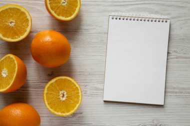 Beyaz ahşap ba üzerinde boş Not Defteri ile yarıya ve tüm portakal