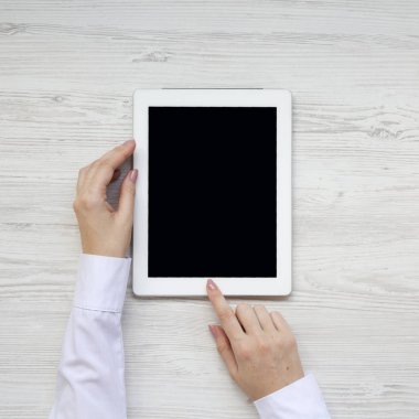 Üstten Görünüm, eller tablet bir beyaz ahşap arka plan üzerinde kullanma