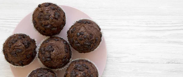 Schokoladenmuffins auf rosa Teller über weißem Holz — Stockfoto