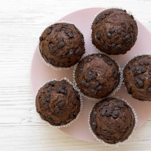 Schokoladen-Cupcakes auf rosa Teller auf weißem Holztisch, Draufsicht — Stockfoto