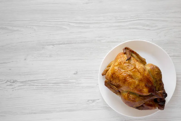 Домашняя вкусная жареная курица на белой тарелке на белом дереве — стоковое фото