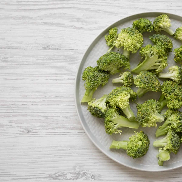 Top vie, taze çiğ brokoli gri beyaz tabakta ahşap kesim — Stok fotoğraf