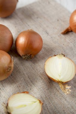 Kumaş, düşük açılı görünümü üzerine soyulmamış çiğ sarı soğan. Yakın çekim.