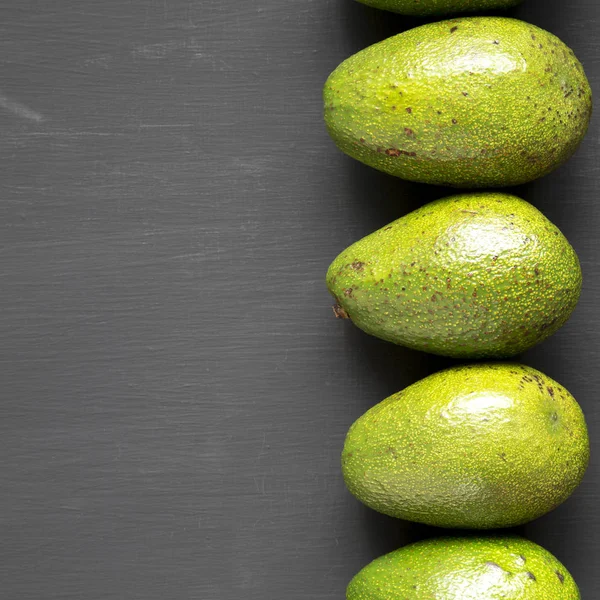 Hele avocado's op donkere zwarte achtergrond, bovenaanzicht. Overhead, fla — Stockfoto