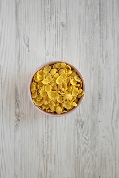 Cornflakes in einer rosafarbenen Schüssel zum Frühstück auf einer weißen hölzernen Surfa — Stockfoto