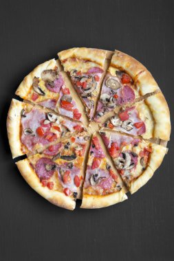 Taze pişmiş pizza Bambu tahta üzerinde siyah yüzey üzerinde. Düz yatıyordu