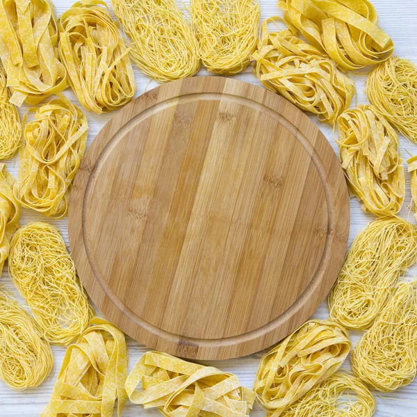 Ongekookte pasta met bamboe bord in het midden op witte houten s — Stockfoto