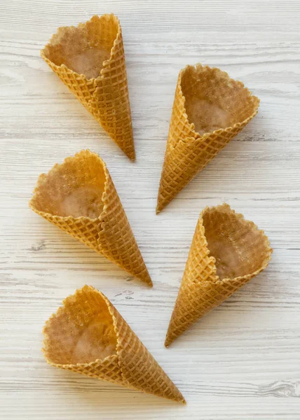 Diseño creativo de conos dulces de gofre sobre una superficie de madera blanca . — Foto de Stock