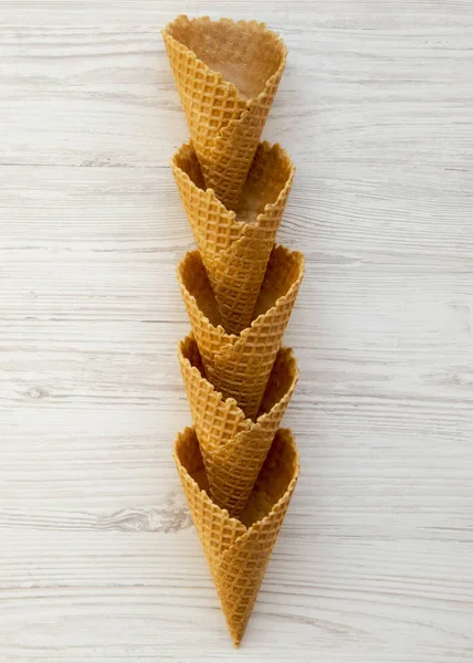 Waffle sweet cones on a white wooden surface. Top view. Flat lay