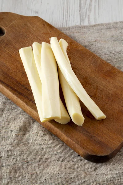 String cheese on rustic wooden board, side view. Healthy snack.