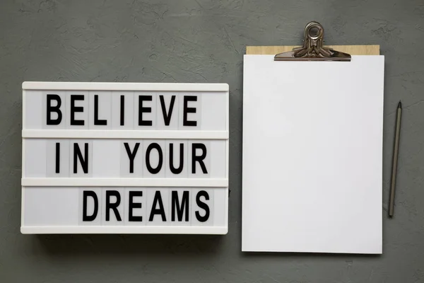 'Believe in your dreams' words on lightbox, clipboard over concr — Stock Photo, Image