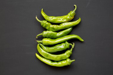 Siyah arka plan, üstten görünüm üzerinde yeşil biber. Düz lay, sağa sola