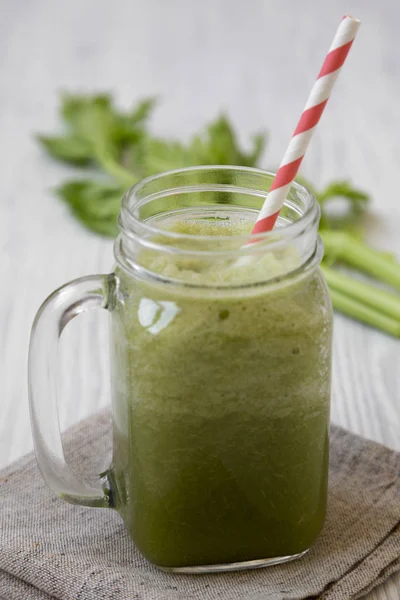 Green celery smoothie in glass jar over white wooden surface, si — Stock Photo, Image