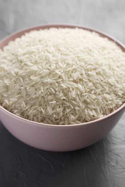 Dry white rice basmati in a pink bowl over concrete background, — Stock Photo, Image