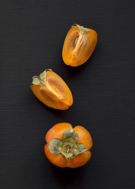 Siyah arka planda, üstten görünüm taze Trabzon hurması. Düz lay, overhea