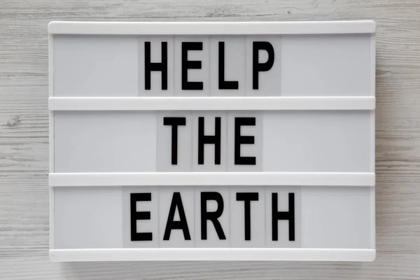 "Pomoci zemi" slova na lightbox bílé dřevěné pozadí, — Stock fotografie