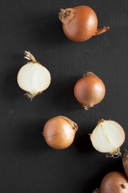 Üstten Görünüm, siyah yüzey üzerinde soyulmamış çiğ sarı soğan. Düz yatıyordu,
