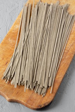 Buğday soba noodle rustik ahşap tahta üzerinde gri arka plan üzerinde düşük açılı görünüş kurumuş. Portre.