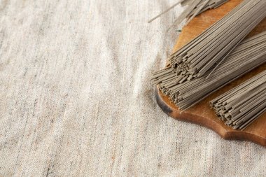 Pişmemiş buğday soba noodle kumaş üzerine rustik ahşap tahta üzerinde,