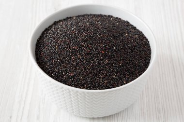 Beyaz ahşap üzerinde bir kase gluten ücretsiz ham organik siyah Quinoa