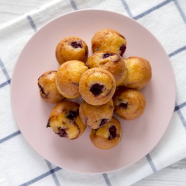 Üst görünüm, pembe plaka üzerinde kiraz ile ev yapımı mini kekler. Düz 