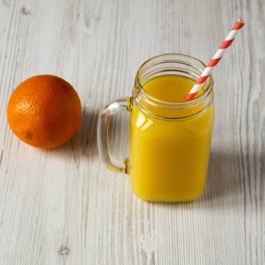 Beyaz ahşap yüzey üzerinde cam kavanoz taze portakal suyu, düşük bir