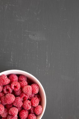 Siyah arka planda pembe bir kase ham ahududu, üst görünüm. Hge