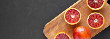 Bütün ve yarıya kan portakal siyah üzerinde rustik ahşap tahta üzerinde