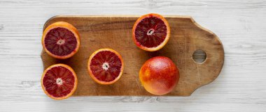 Beyaz ahşap yüzeyde rustik ahşap tahta üzerinde kan portakalları, 