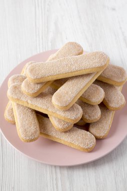 Beyaz ahşap üzerinde pembe plaka üzerinde Savoiardi veya kedi dili çerezler