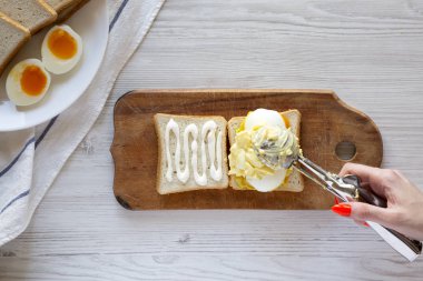 Beyaz woode üzerinde kahvaltı için yumurta sandviç adım adım yemek