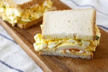 Rustik ahşap tahta üzerinde kahvaltı için ev yapımı yumurta sandviç, yan