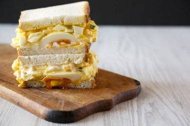 Rustik ahşap tahta üzerinde kahvaltı için ev yapımı yumurta sandviç, yan