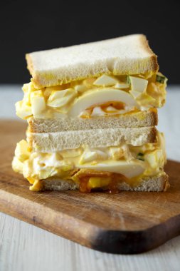 Rustik ahşap tahta üzerinde kahvaltı için ev yapımı yumurta sandviç, yan