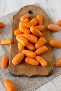 Rustik ahşap tahta üzerinde lezzetli soyulmuş bebek havuç, yan görünüm. Clo