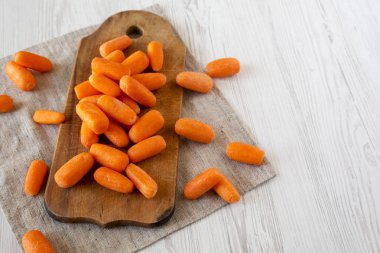 Rustik ahşap tahta üzerinde lezzetli soyulmuş bebek havuç, yan görünüm. Clo