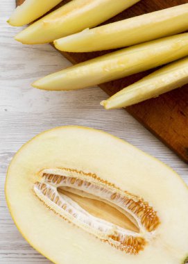 Beyaz ahşap yüzeyde dilimlenmiş kavun, üst görünüm. Düz yatıyordu, üzerinde