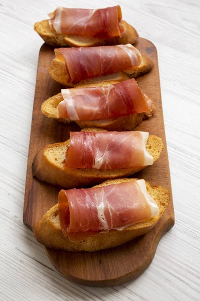 Crostini con jamón serrano sobre tabla de madera rústica, vista de ángulo bajo — Foto de Stock