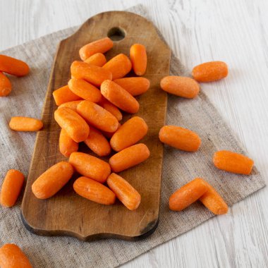Fresh baby carrots on rustic wooden board, side view. Close-up.  clipart