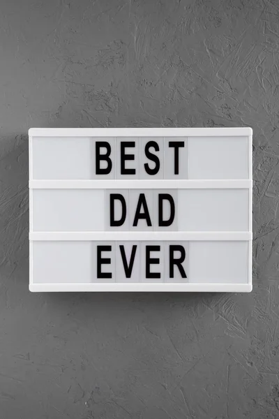 Modern board with \'Best dad ever\' words over concrete surface, t