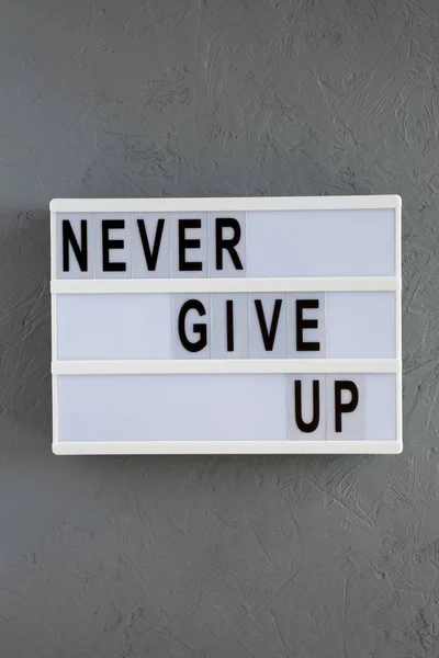 Modern board with 'Never give up' words over gray background. Fl — Stock Photo, Image