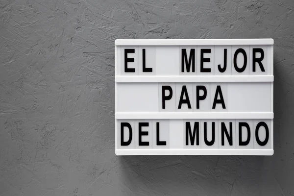 Τα λόγια του "Ελ Μέτζορ Πάπα Ντελ Μούντο" στο φως πάνω από την γκρίζα επιφάνεια. O — Φωτογραφία Αρχείου