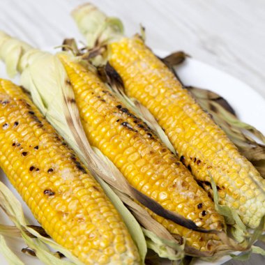 Beyaz yuvarlak plaka, yan görünüm üzerinde koçan üzerinde ızgara mısır. Yakın