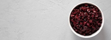 Gri arka plan üzerinde bir kapta kuru organik kızılcık, üst görünümü