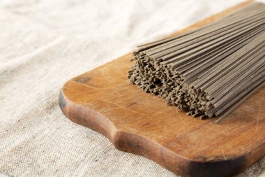 Rustik ahşap tahta üzerinde kurutulmuş karabuğday soba erişte, yan görünüm. 