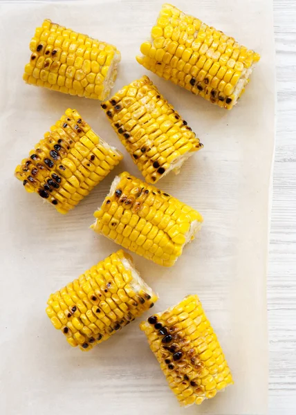 Grilled corn on the cob over white wooden surface, top view. Sum