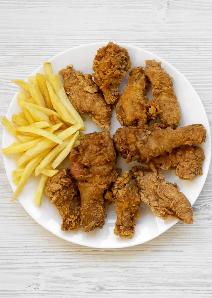 Tasty fried chicken drumsticks, spicy wings, French fries and ch